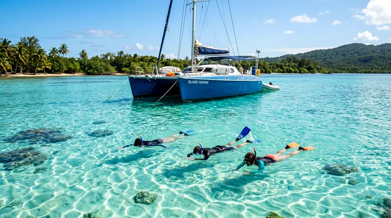 Small 12-person catamaran at anchor with two couples swimming in lagoon below
